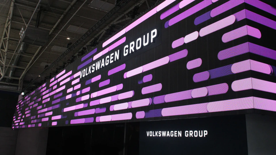 Volkswagen Group lettering over the generative composition wrapping the corner of the booth's LED wall