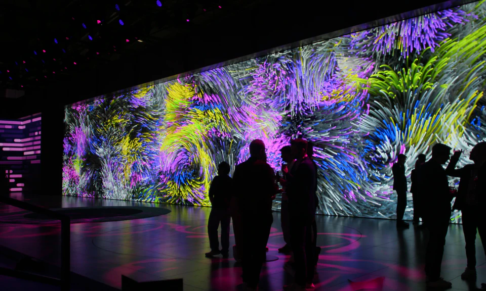 Visitors standing in front of the LED wall as a painterly generative composition shifts across it