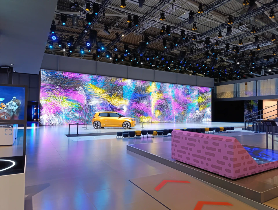 Overview of the Volkswagen Group booth — the generative LED wall behind the vehicle display and seating areas